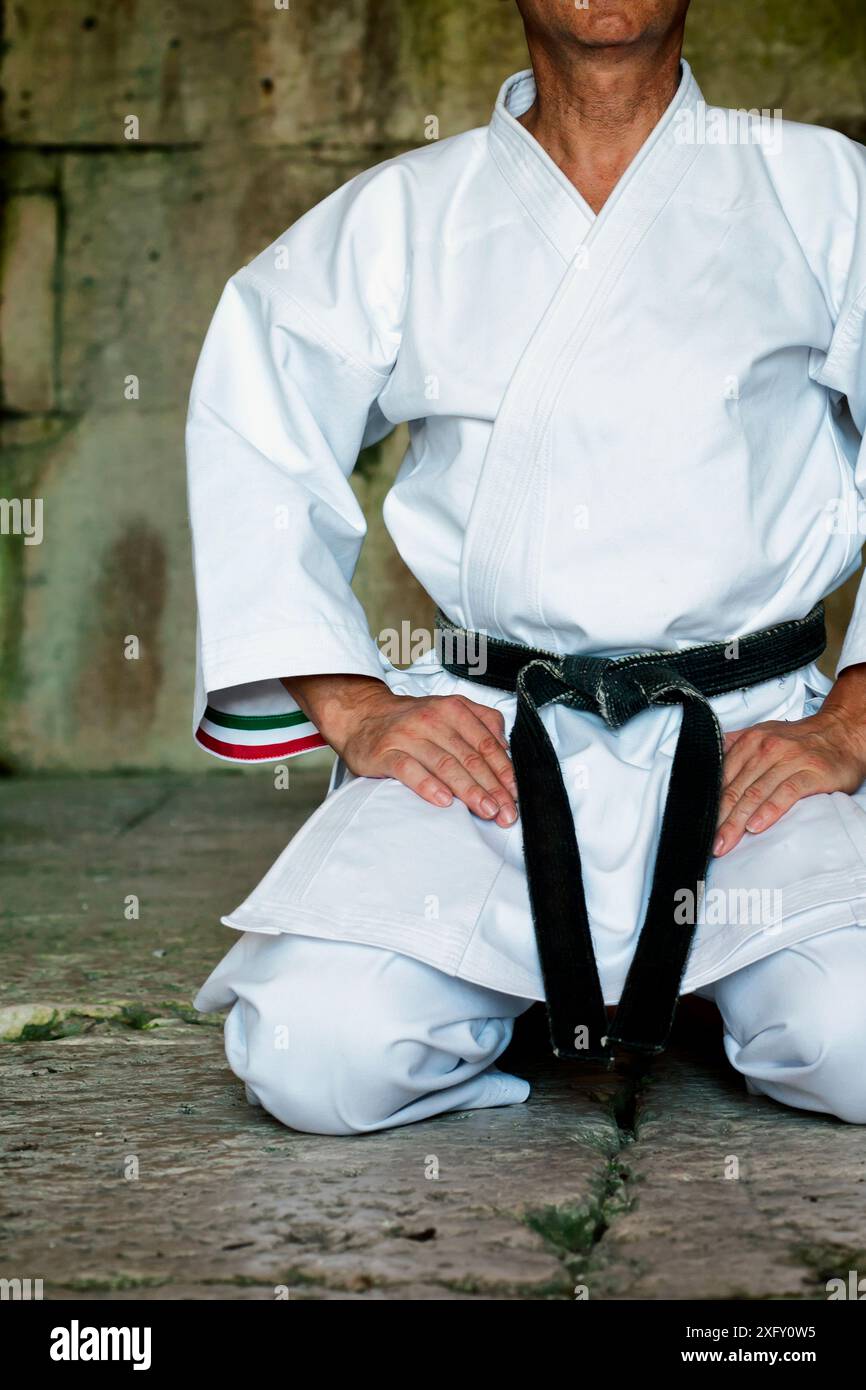 Schwarzer Gürtel Karate Mann sitzen auf EINER Position zu beginnen oder beenden Üben. Stockfoto