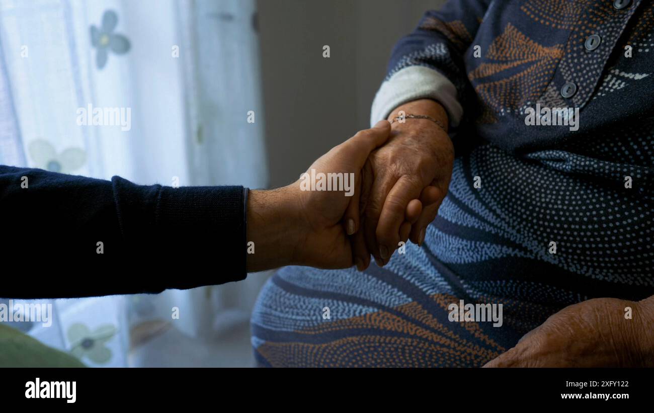 Konzept der Unterstützung und Begleitung älterer Menschen. Eine junge Hand streichelt die Hand einer älteren Frau. Stockfoto
