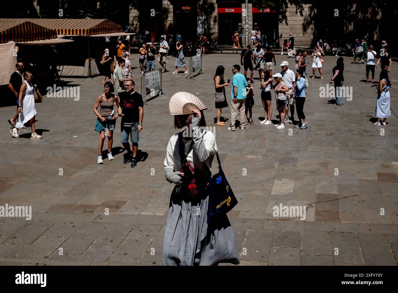 Ein Tourist benutzt einen Ventilator, um sich vor der Sonne in der Innenstadt von Barcelona zu schützen. Stockfoto
