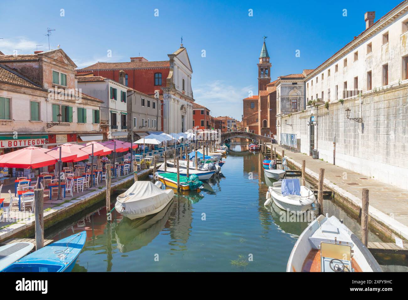 Die Kanalvene mit verankerten mehrfarbigen Booten, die Filippini-Kirche, der Glockenturm der Kirche San Giacomo Apostolo, Chioggia, Stadt der Metropolstadt Venedig, Veneto, Italien Stockfoto