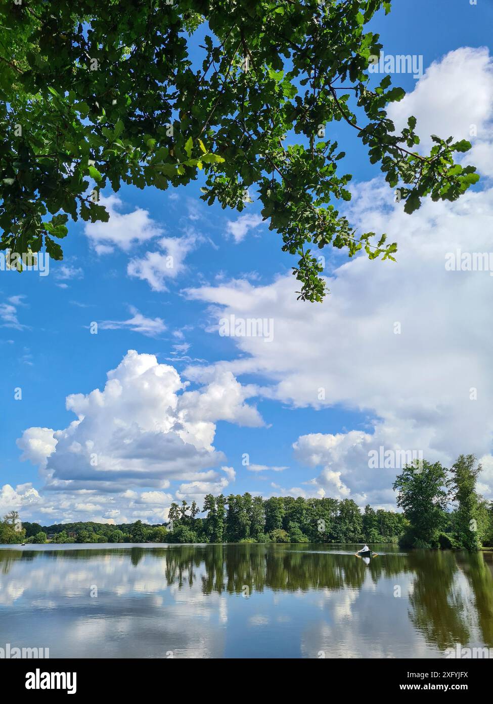 In der Ferne auf dem See kann man eine Person allein im Kanu sehen, im Hintergrund schwere Wolken am Himmel über einem See an einem Sommertag im August, Klimawandel, Nordrhein-Westfalen, Deutschland Stockfoto