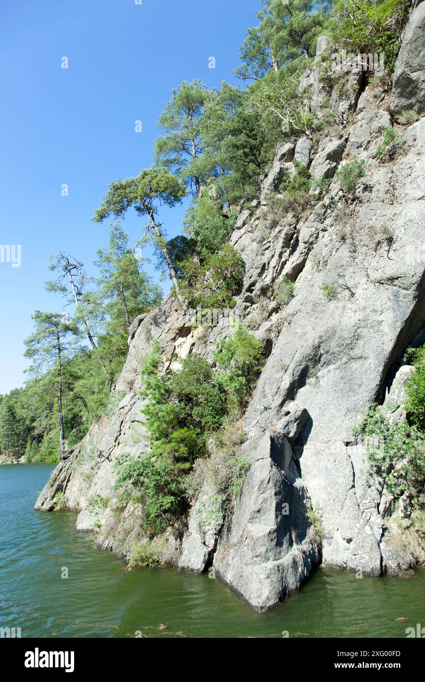 Der Blick auf das steile Ufer des Karacaoren-Sees mit Bäumen, die auf Felsen wachsen, in der Provinz Antalya (Türkei). Stockfoto