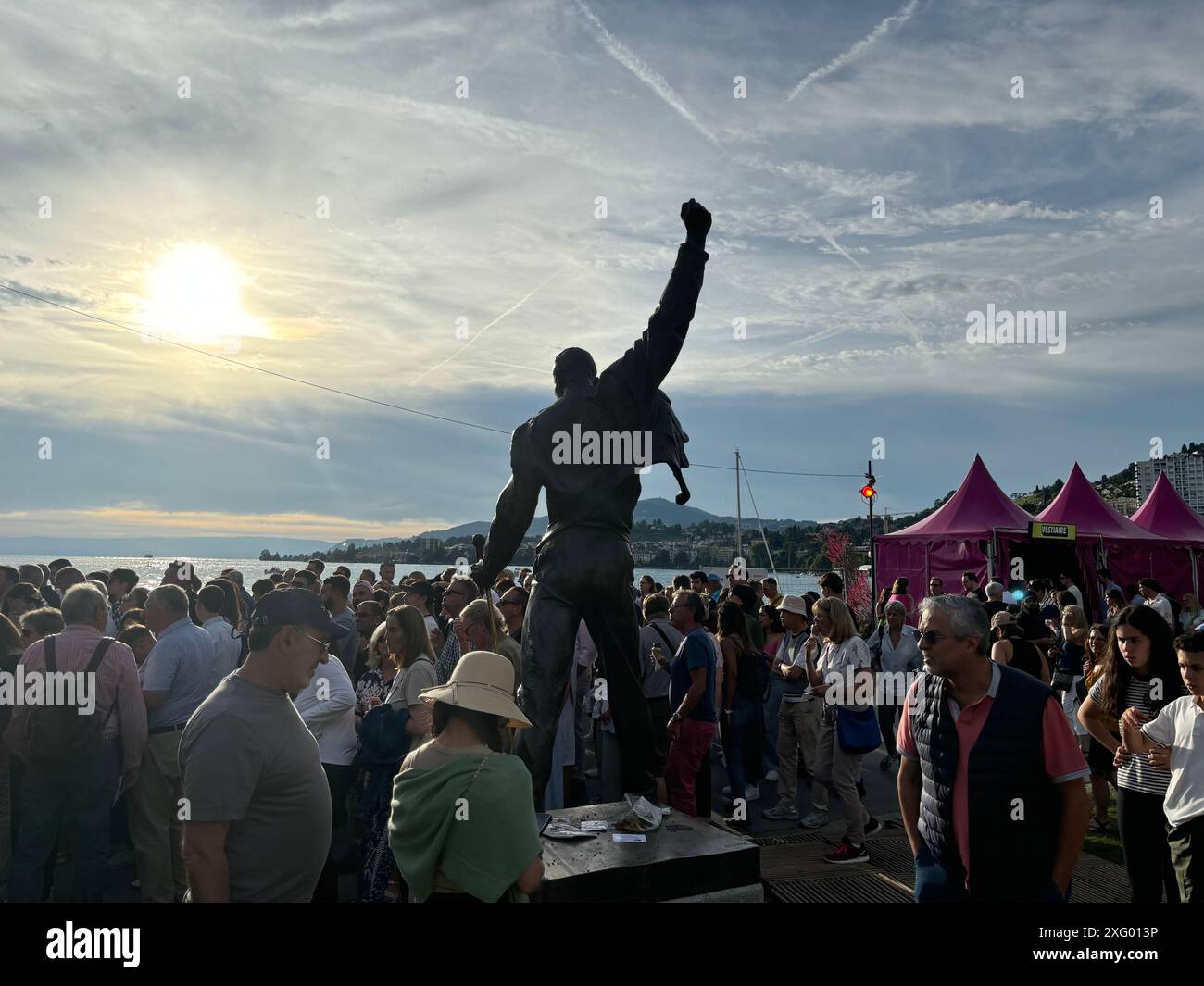Montreux, Schweiz. Juli 2024. Besucher des 58. Montreux Jazz Festivals stehen hinter der Bronzestatue von Freddie Mercury der Künstlerin Irena Sedlecká am Ufer des Genfer Sees. Quelle: Christiane Oelrich/dpa/Alamy Live News Stockfoto