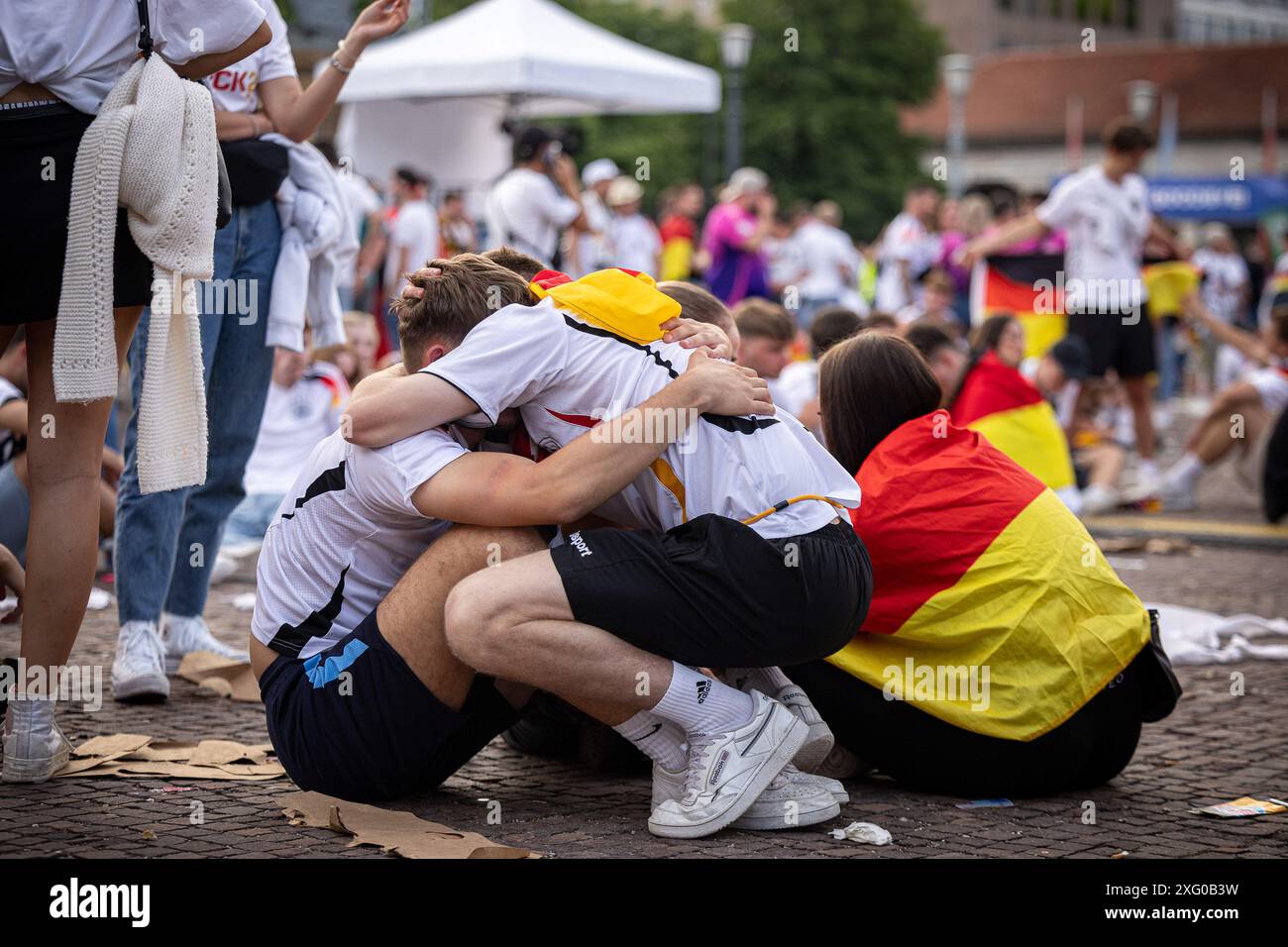 Zwei deutschland Fans sitzen niedergeschlagen am Boden und umarmen sich gegenseitig. Fans der deutschen Nationalmannschaft liegen in Traenen nach dem Spiel gegen Spanien und dem Ausscheiden aus der EURO2024 beim Fanfest mit Public Viewing auf dem Stuttgarter Schlossplatz. Foto: Eibner-Pressefoto/Dennis Duddek Stockfoto