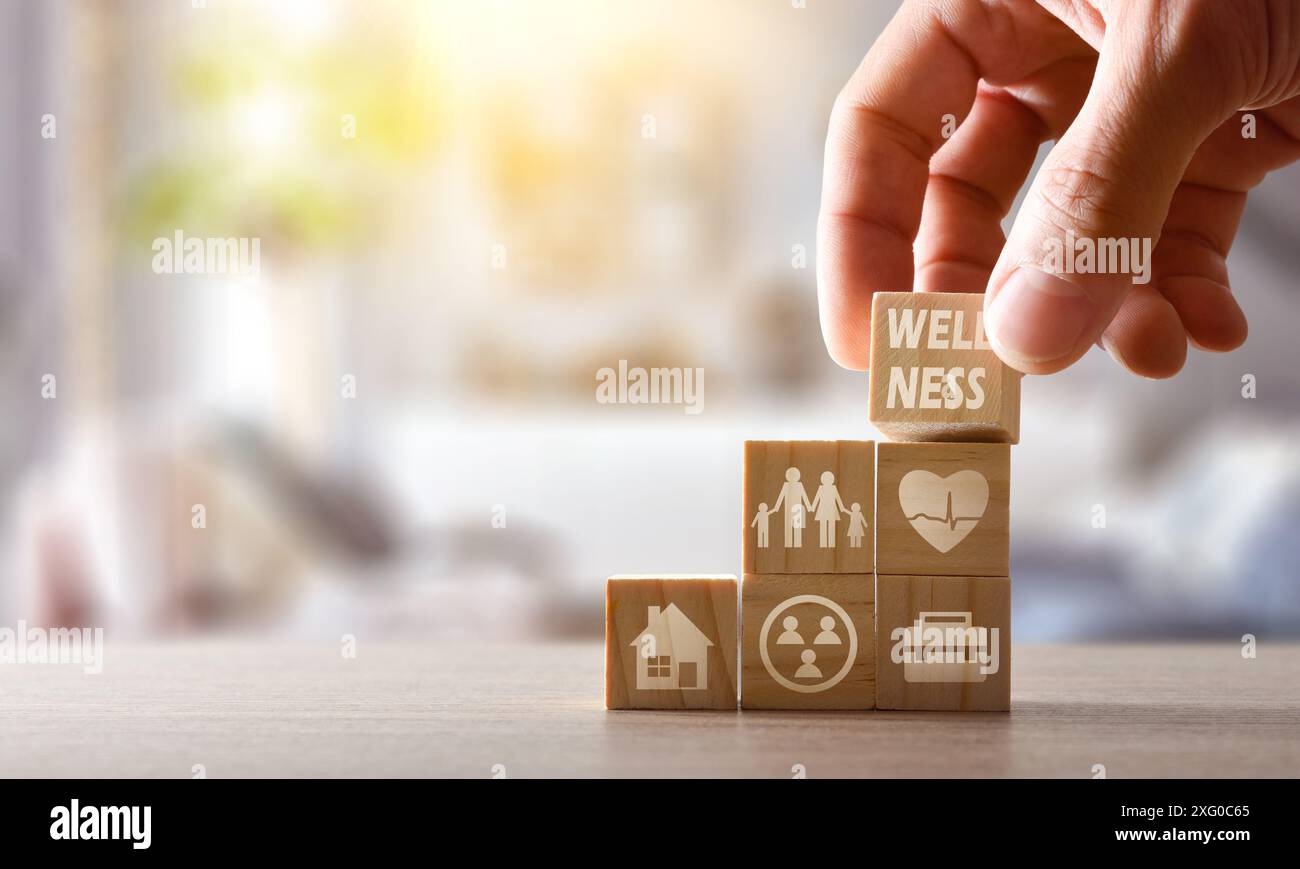 Soziales und persönliches Wellnesskonzept mit handstapelbaren Holzwürfeln auf einem Tisch zu Hause mit Symbolen für Gesundheit, Familie, Arbeit, Zuhause und Sozia Stockfoto