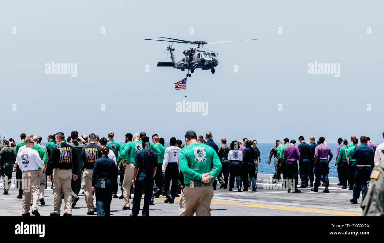 Eine MH-60R Seahawk, die der Helicopter Maritime Strike Squadron (HSM) 46 zugeordnet ist, führt am 4. Juli 2024 eine amerikanische Flagge über dem Flugdeck des Flugzeugträgers USS George Washington (CVN 73) der Nimitz-Klasse. George Washington wird als Teil von Southern Seas 2024 eingesetzt, das durch gemeinsamen, multinationalen und interinstitutionellen Austausch und Zusammenarbeit die Fähigkeiten, die Interoperabilität und die Stärkung der maritimen Partnerschaften mit Ländern im gesamten Zuständigkeitsbereich des US-amerikanischen Südkommandos verbessern soll. (Foto der US Navy von Mass Communication Specialist 3rd Class Stockfoto