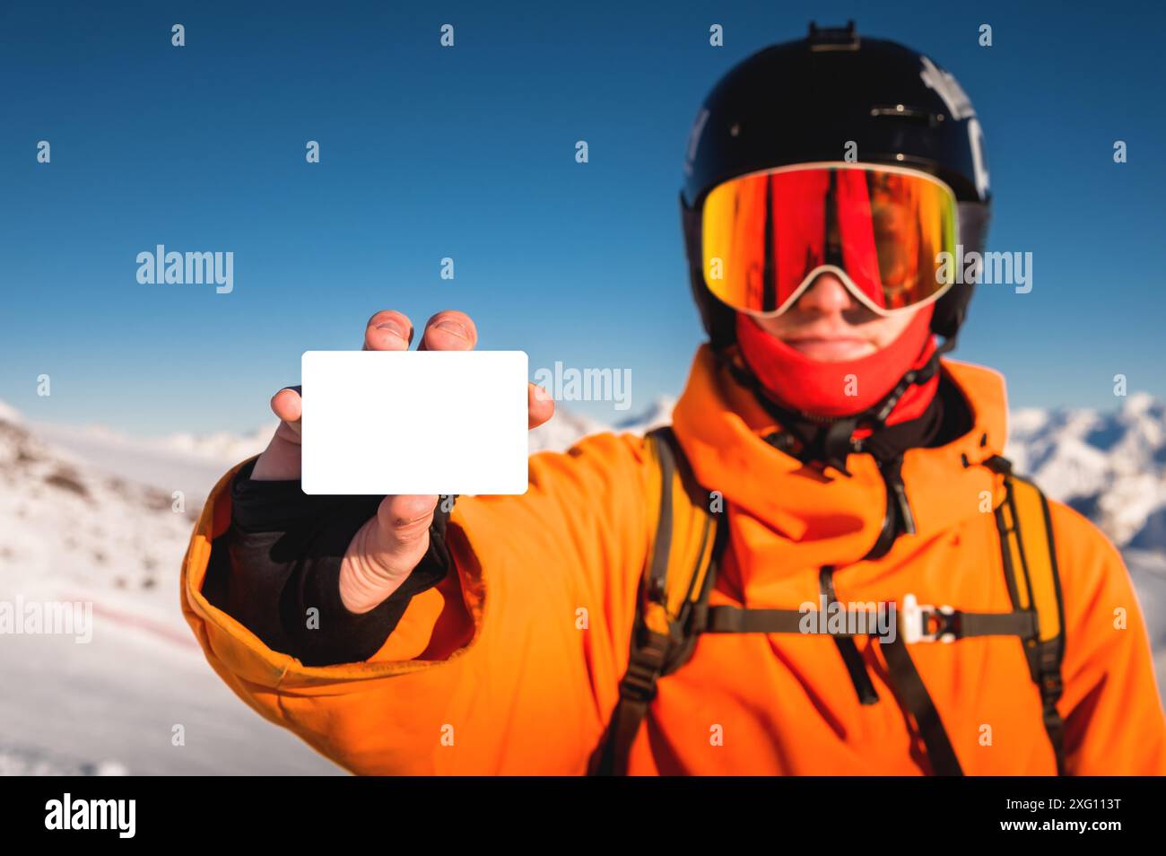 Snowboarder oder Skifahrer halten leeren Liftpass in der Hand, Porträt mit Berg im Hintergrund. Skipass in der Hand aus nächster Nähe Stockfoto