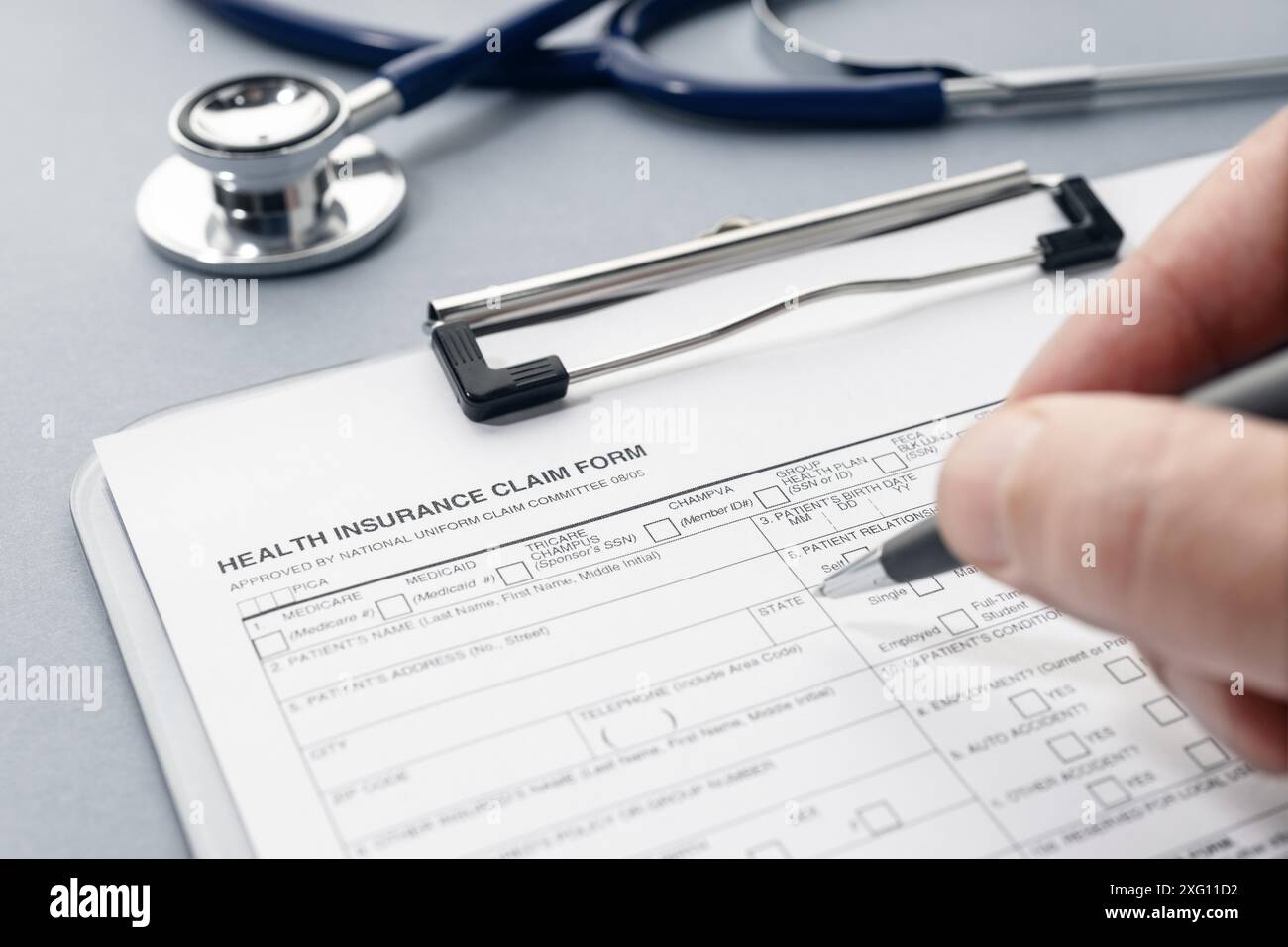 Füllen Sie das Antragsformular für die Krankenversicherung und das Stethoskop auf dem Schreibtisch manuell aus Stockfoto