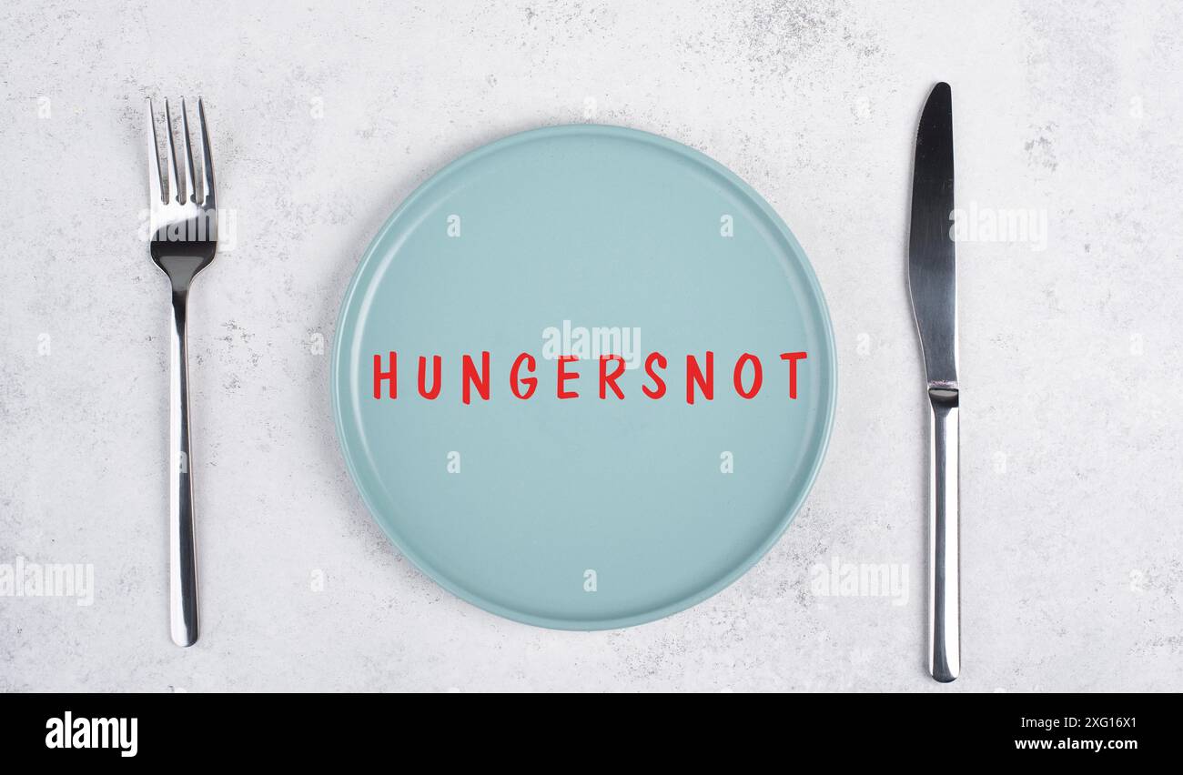 Hungersnot steht in deutscher Sprache auf dem Teller, Lebensmittelknappheit und Hungersnot wegen des Krieges und der Inflation, politische Frage Stockfoto