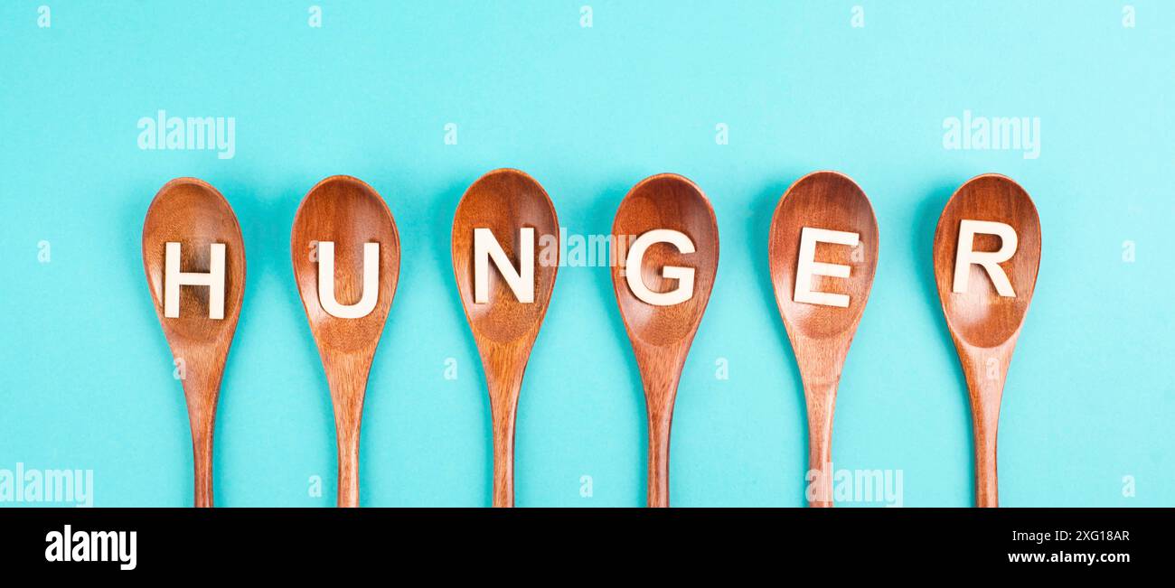 Hunger steht in deutscher Sprache auf den Holzlöffeln, Lebensmittelknappheit und Hunger wegen des Krieges und der Inflation, politische Frage Stockfoto Hunger steht in deutscher Sprache auf den Holzlöffeln, Lebensmittelknappheit und Hunger wegen des Krieges und der Inflation, politische Frage Stockfoto
