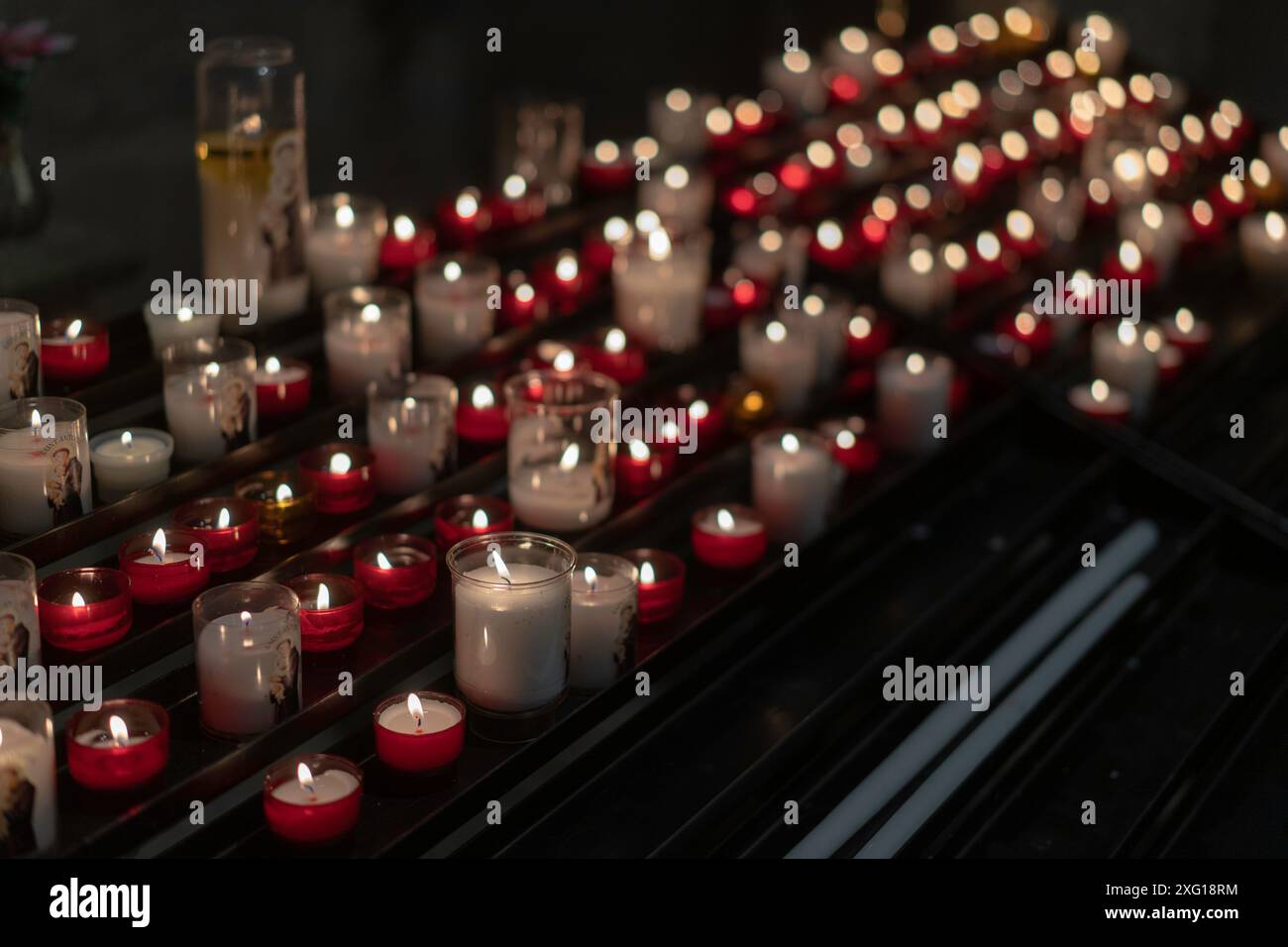 Kerzen in der Kirche hintereinander, Kerzen zum Gebet rot-weißes Licht Stockfoto