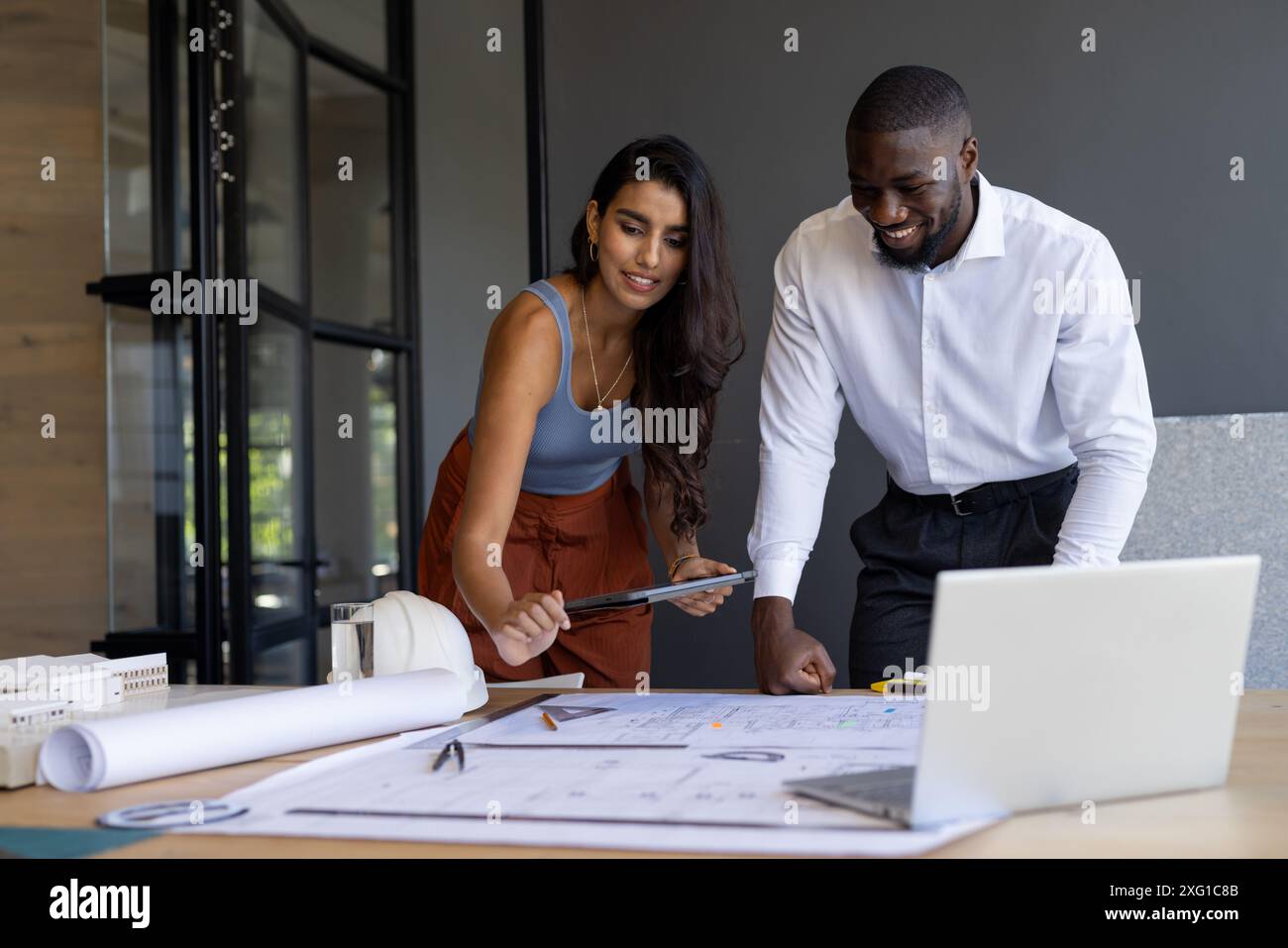 Zusammenarbeit am Projekt, Kollegen, die Blaupausen überprüfen und Tablet im Büro verwenden Stockfoto