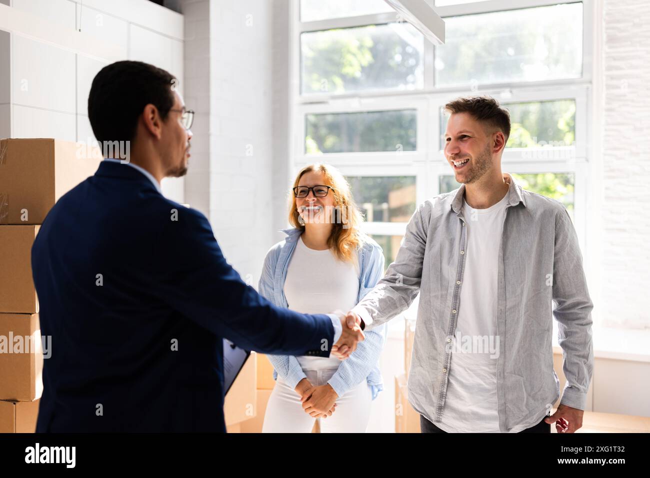 Glückliches Paar feiert den Kauf eines neuen Hauses mit einem Immobilienmakler im Büro und schließt einen finanziellen Deal für den Immobilienbesitz ab. Stockfoto