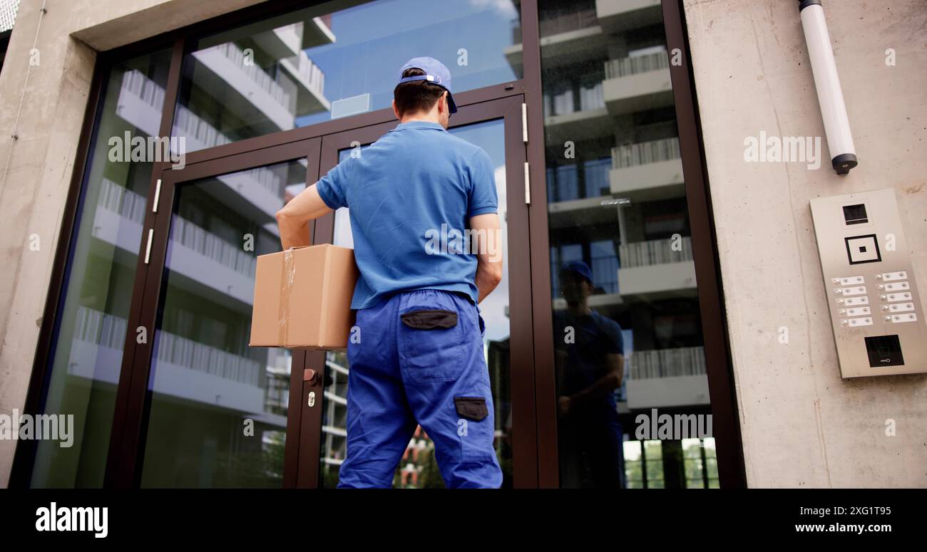 Professioneller Kurier, der sichere Lieferungen mit fortschrittlichem Sprechanlage am Gebäudeeingang ermöglicht und Pakete mit Identitätsüberprüfung liefert. Stockfoto