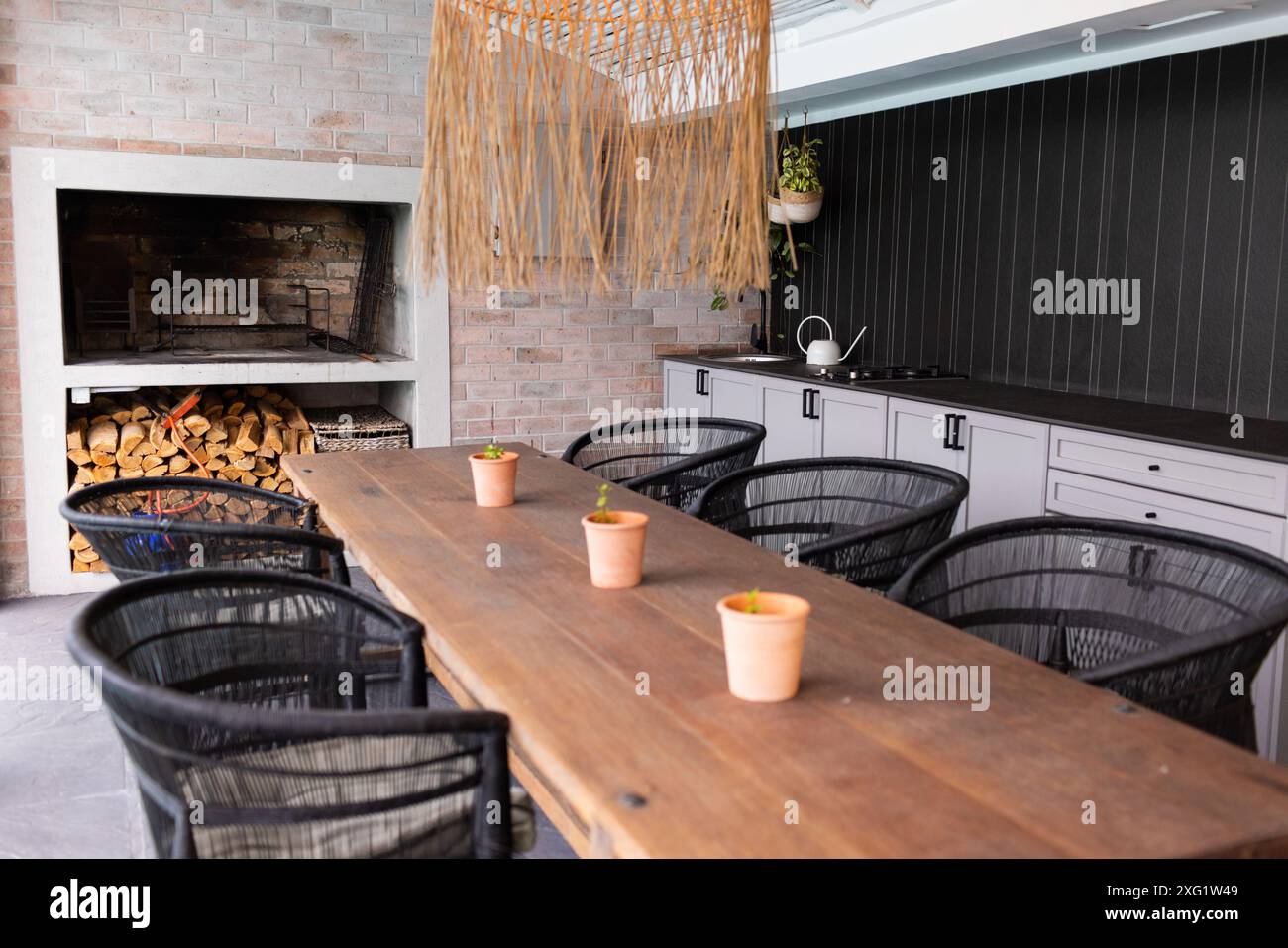 Moderne Küche mit Esstisch aus Holz, schwarzen Stühlen und Topfpflanzen, Kopierraum Stockfoto