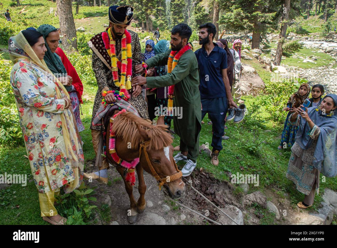 Verwandte machen Fotos von einem Gujjar (Nomaden) Bräutigam, der während der Hochzeitszeremonie im Dorf Sangerwani im Bezirk Pulwama, 75 km südlich von Srinagar, der Sommerhauptstadt der Himalaya-Region in Kaschmir, in das Haus der Braut reist. Trotz der exponentiellen Entwicklung von Autos verwenden einige nomadische Stämme noch Pferde und Palanquins für Hochzeiten. Eine neue Studie der Tribal Research and Cultural Foundation, einer Frontalorganisation der Gujjar-Gemeinschaft, zeigt, dass 88 Prozent der Gujjars (Nomaden) in Jammu und Kaschmir bis zu 600 US-Dollar für eine Hochzeitszeremonie ausgeben, und 89 Stockfoto