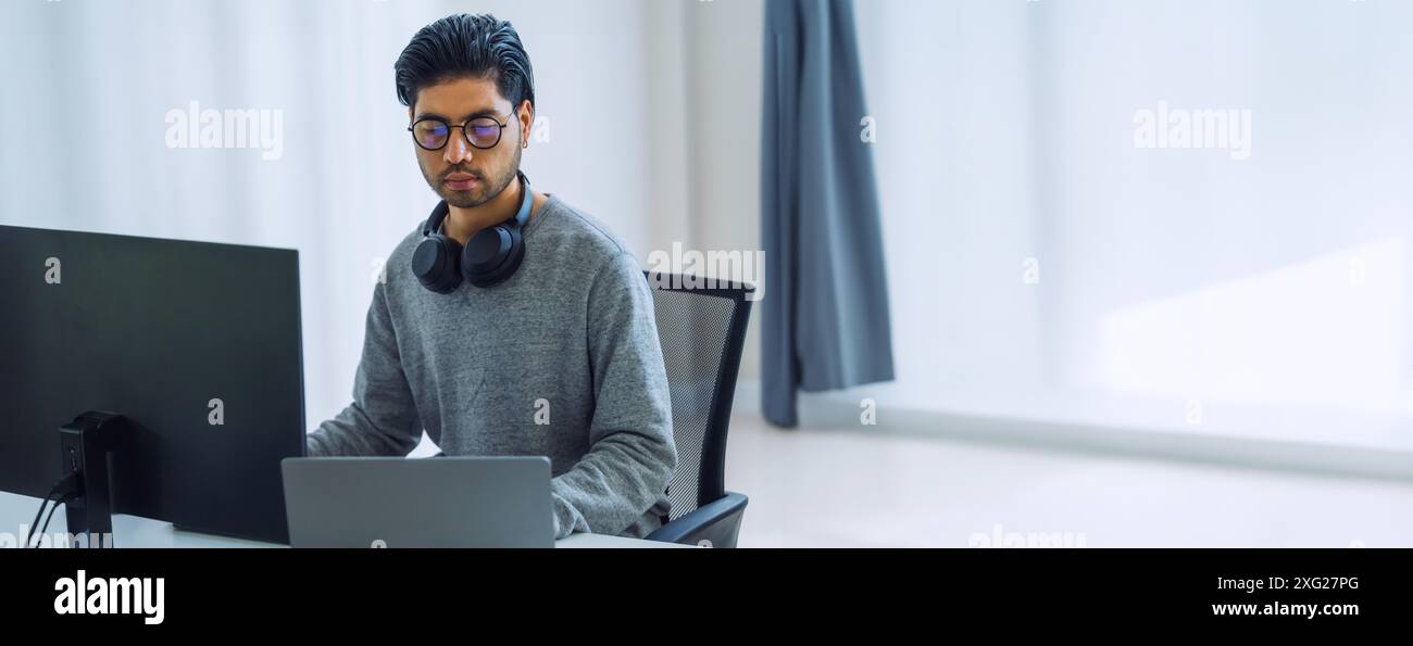 Der Prompt-Ingenieur des asiatischen Mannes entwickelt eine Codierungs-App mit Softwaredaten, die vor dem Computermonitor im Büro sitzen Stockfoto