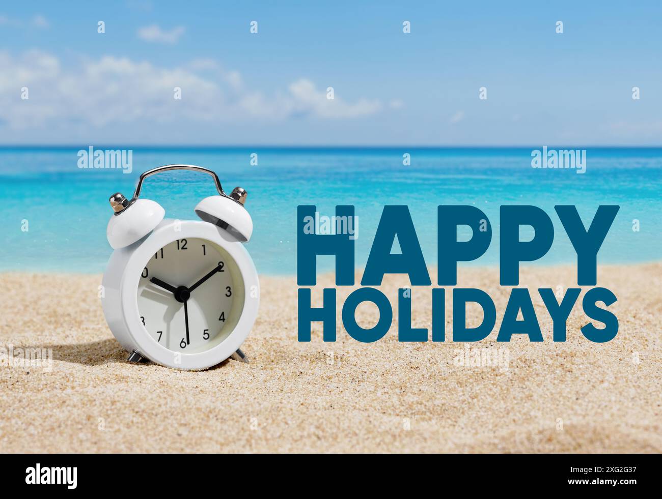 Ein Wecker am Strand mit dem Wort Happy Holidays. Sommerurlaub oder Urlaubskonzept. Stockfoto