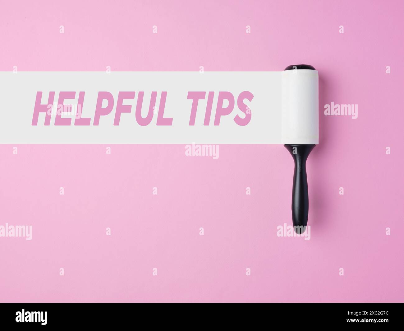 Hilfreiche Tipps. Nützliche Tipps, Ratschläge und Tricks für Unternehmen und Privatleben. Fusselrolle mit weißer Spur auf rosafarbenem Hintergrund mit der Nachricht hilfreiche Tipps. Stockfoto