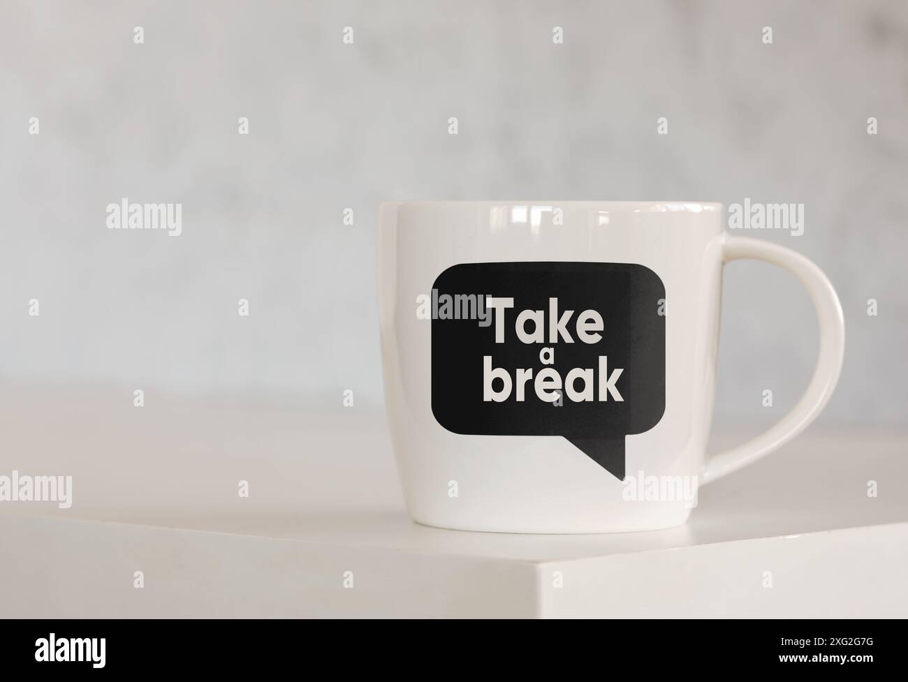 Die Nachricht Take a Break auf einer Sprechblase, die auf einer Kaffeetasse über dem Tisch gedruckt ist. Geschäftskonzept für Pause und Pause am Arbeitsplatz. Stockfoto