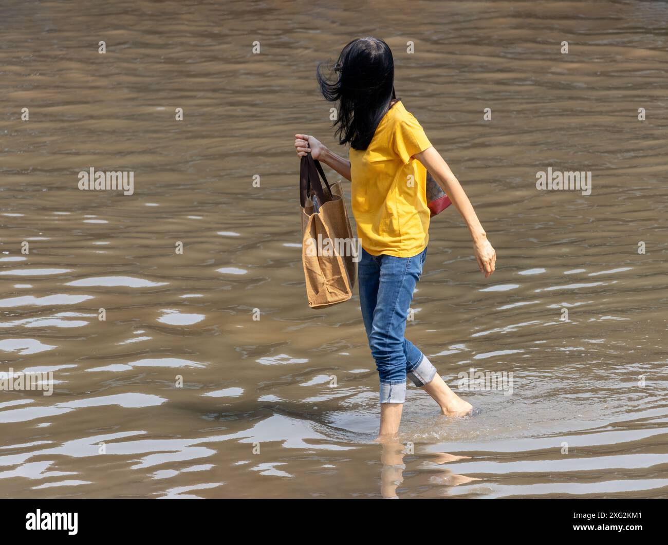 Eine Frau läuft auf einer überfluteten Straße, Bangkok, Thailand Stockfoto