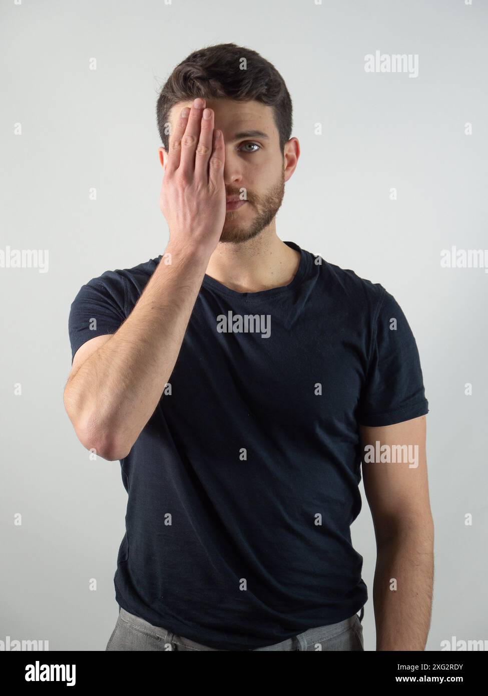 Ein Mann wird mit seinem Gesicht und einem Auge von seiner Hand gesehen, in einer Geste der Not oder Traurigkeit. Seine Finger wirken angespannt und vermitteln tiefe Emotionen durch Körpersprache. Stockfoto