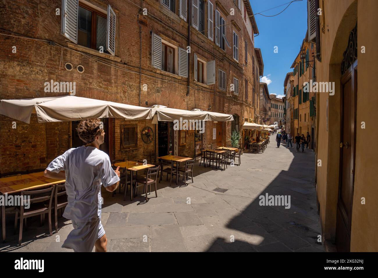 Siena, Italien - 01. Juni 2024: Schöne Straße von siena. Running man im Vordergrund. Stockfoto