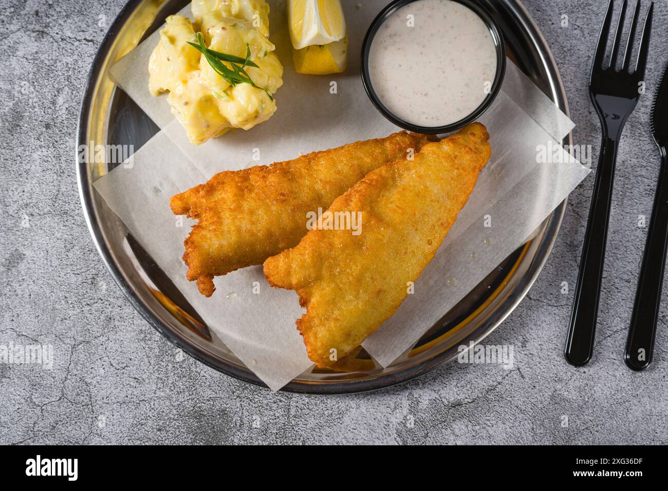 Frittiertes, beschichtetes Fischfilet mit Kartoffelsalat auf Steintisch Stockfoto