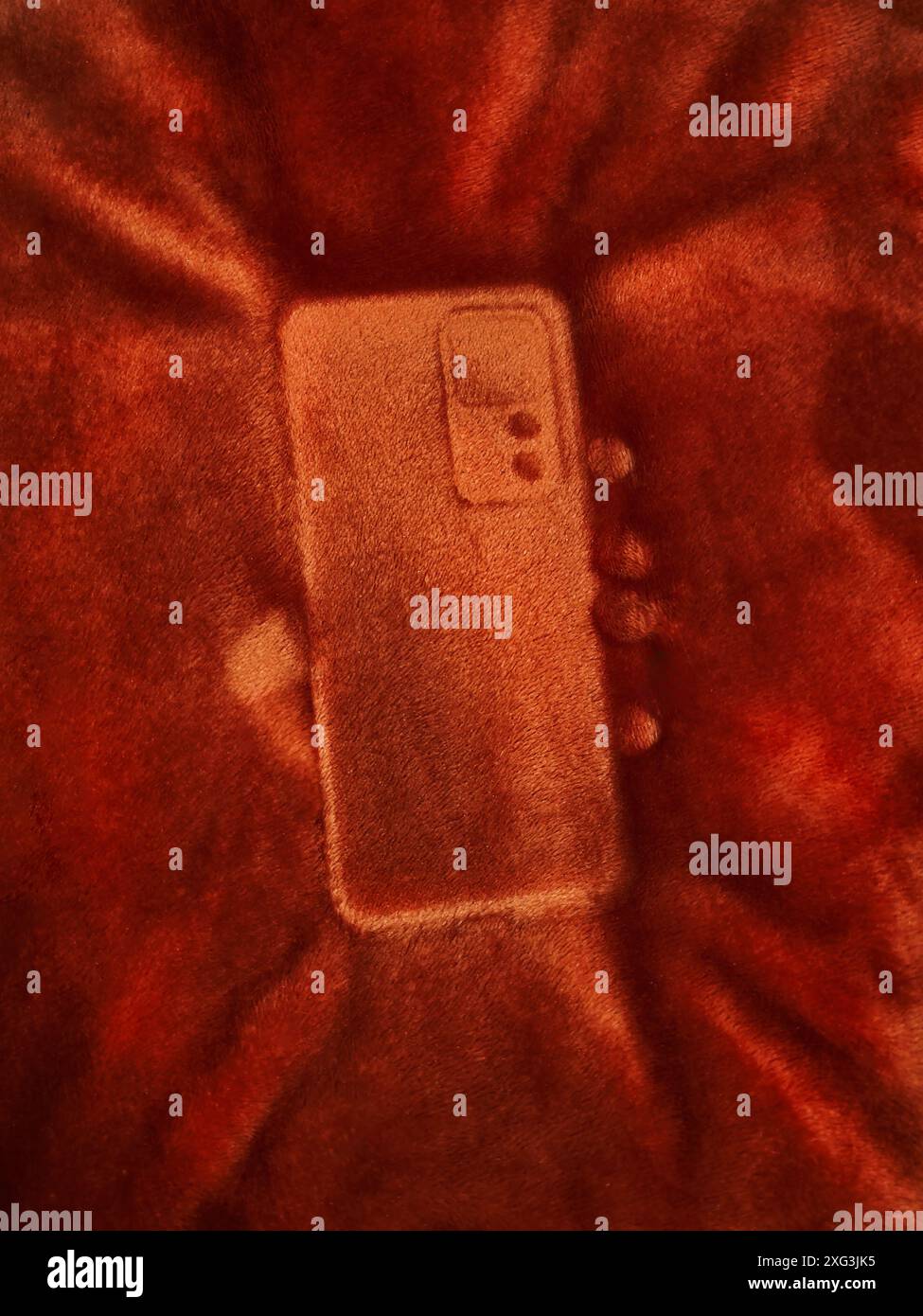 Telefonmarke auf einer flauschigen Decke. Detaillierter Ausdruck eines Telefons auf einer weichen Bettdecke. Umrissmarke eines Mobiltelefons. Stockfoto