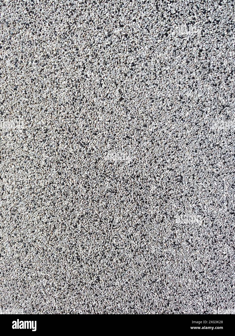 Nahaufnahme einer rauen, grauen Oberfläche, die an Beton oder Stuck erinnert. Die körnige Qualität und die ungleichmäßige Schattierung machen es geeignet für Stockfoto
