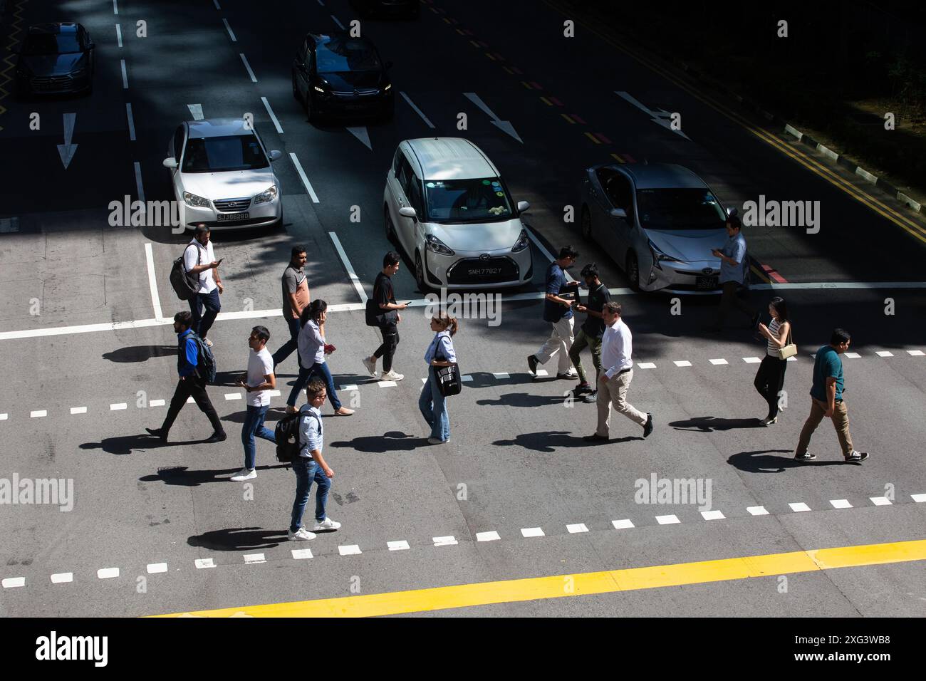 Fußgänger überqueren die Straße bei heißem Wetter in Singapur, Südostasien. Stockfoto