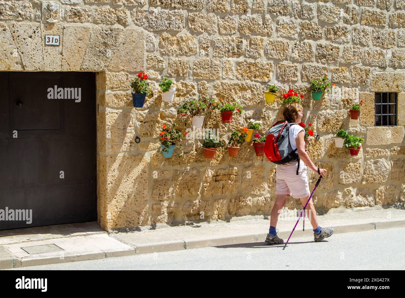 Frau, die auf dem Jakobsweg durch das spanische Dorf Hornillos del Camino in Kastilien und Leon Spanien geht Stockfoto