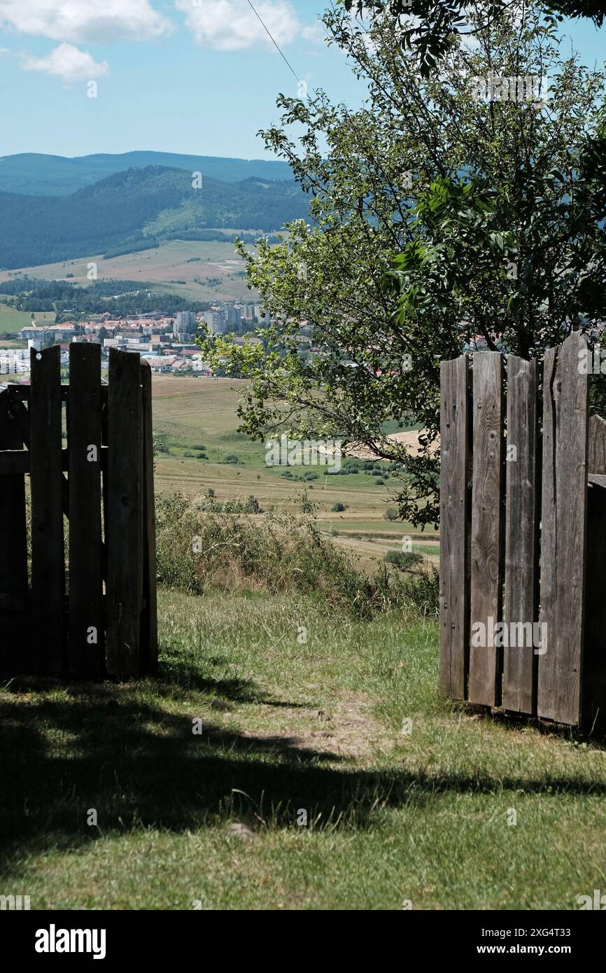 Malerischer Blick durch ein hölzernes Tor auf die Hügel und das Dorf an einem sonnigen Tag Stockfoto