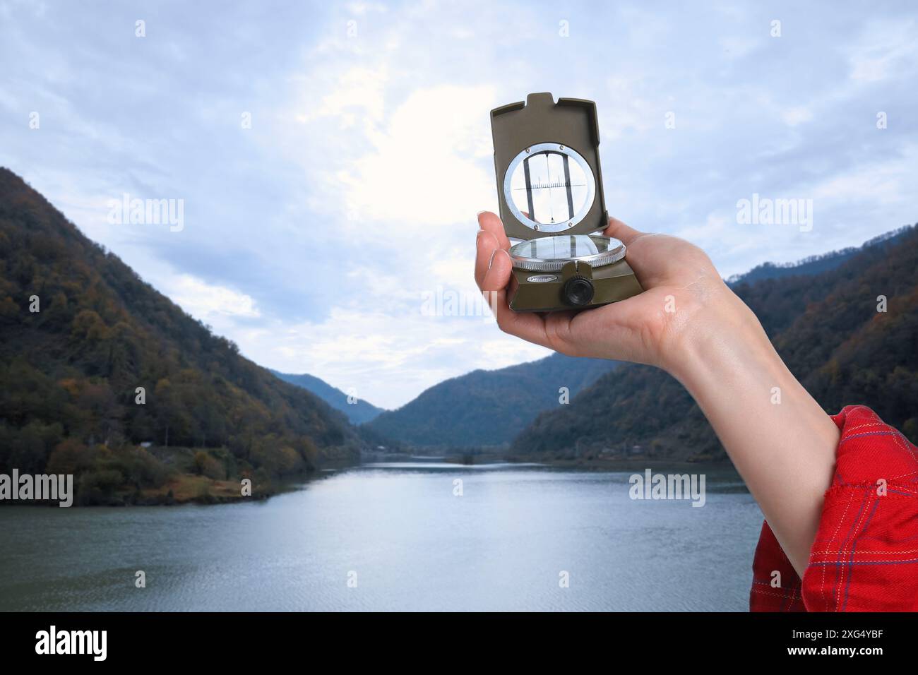 Frau, die den Kompass in den Bergen benutzt, Nahaufnahme. Navigationsinstrument Stockfoto