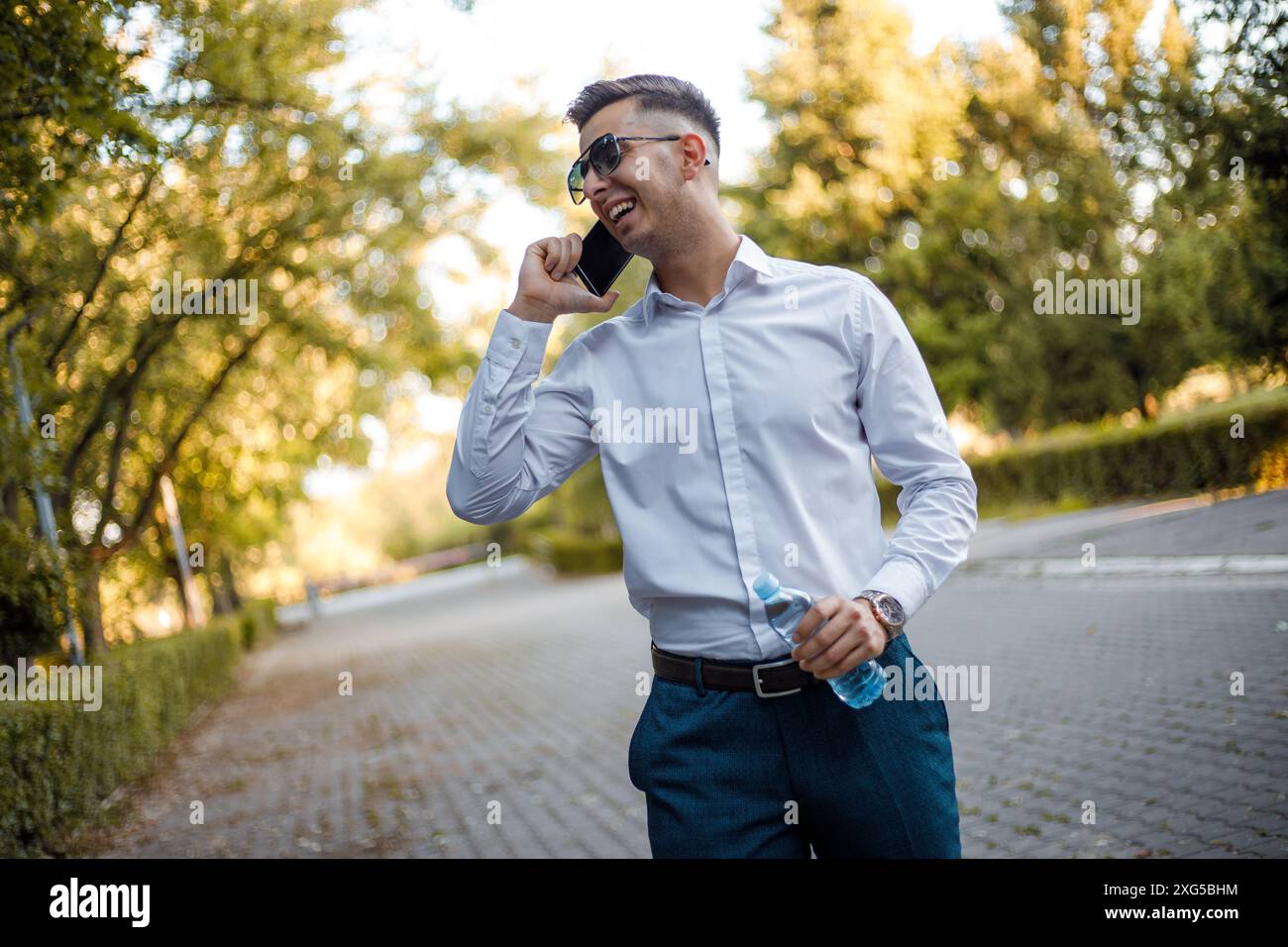 Ein Mann steht auf einer belebten Stadtstraße und führt ein Telefongespräch. Er scheint auf seinen Anruf konzentriert zu sein. Stockfoto