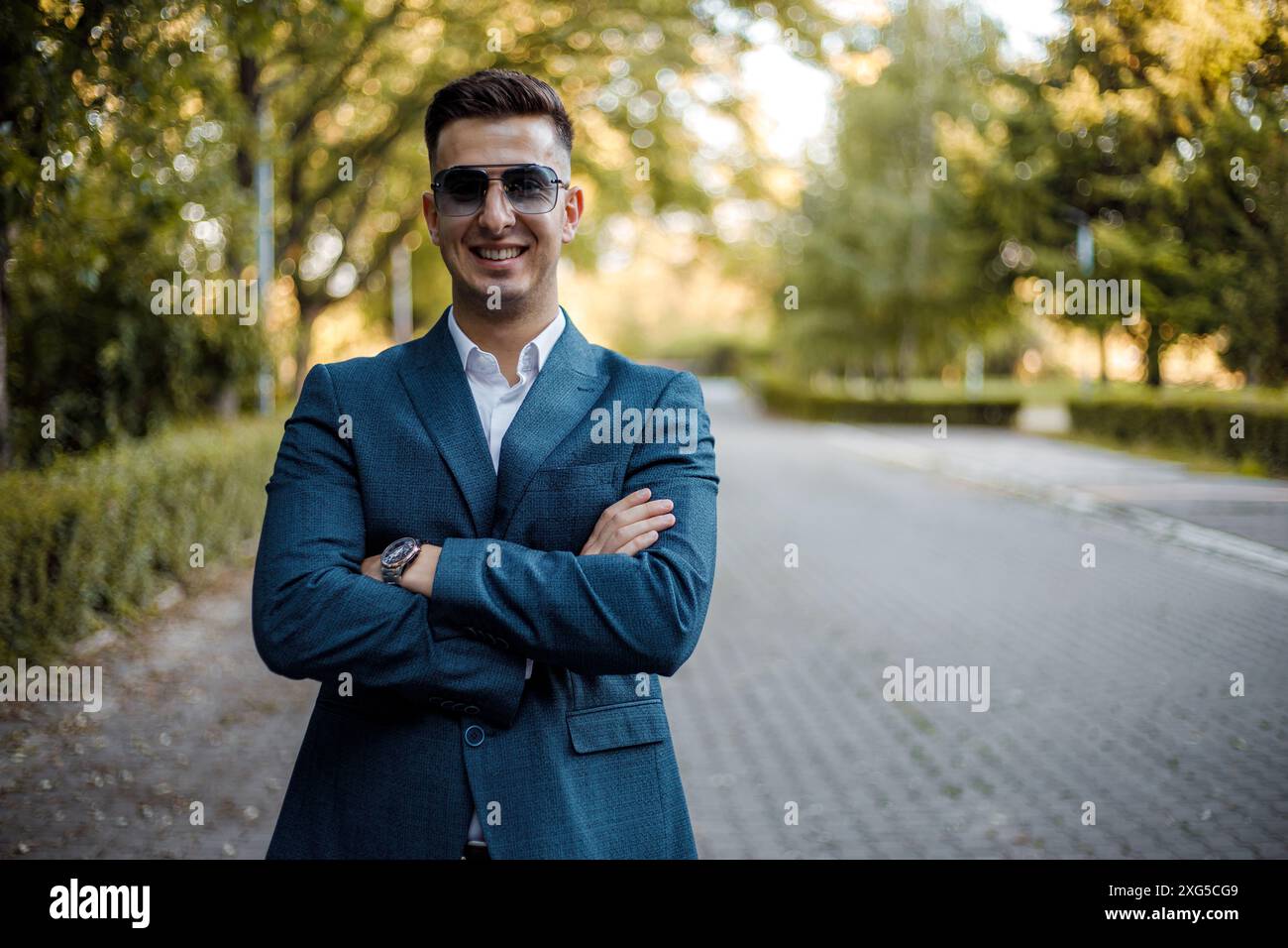 Ein Mann in Anzug und Sonnenbrille steht selbstbewusst mitten auf einer Straße und scheint fokussiert und kontrolliert seine Umgebung. Stockfoto
