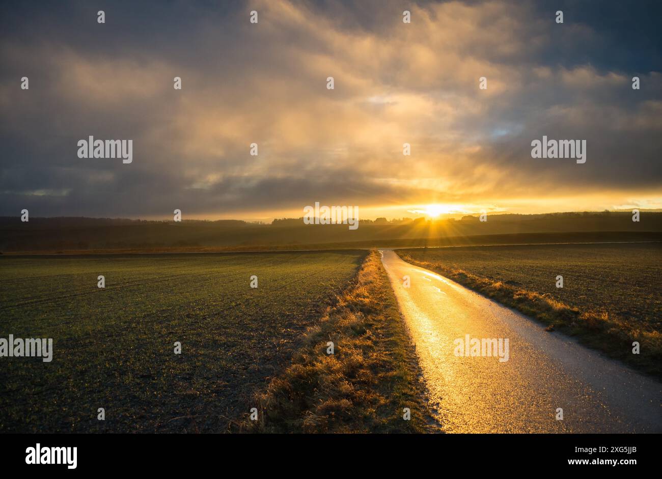 Dramatischer Sonnenuntergang und weiße Linie auf Asphaltstraße zum Horizont Stockfoto