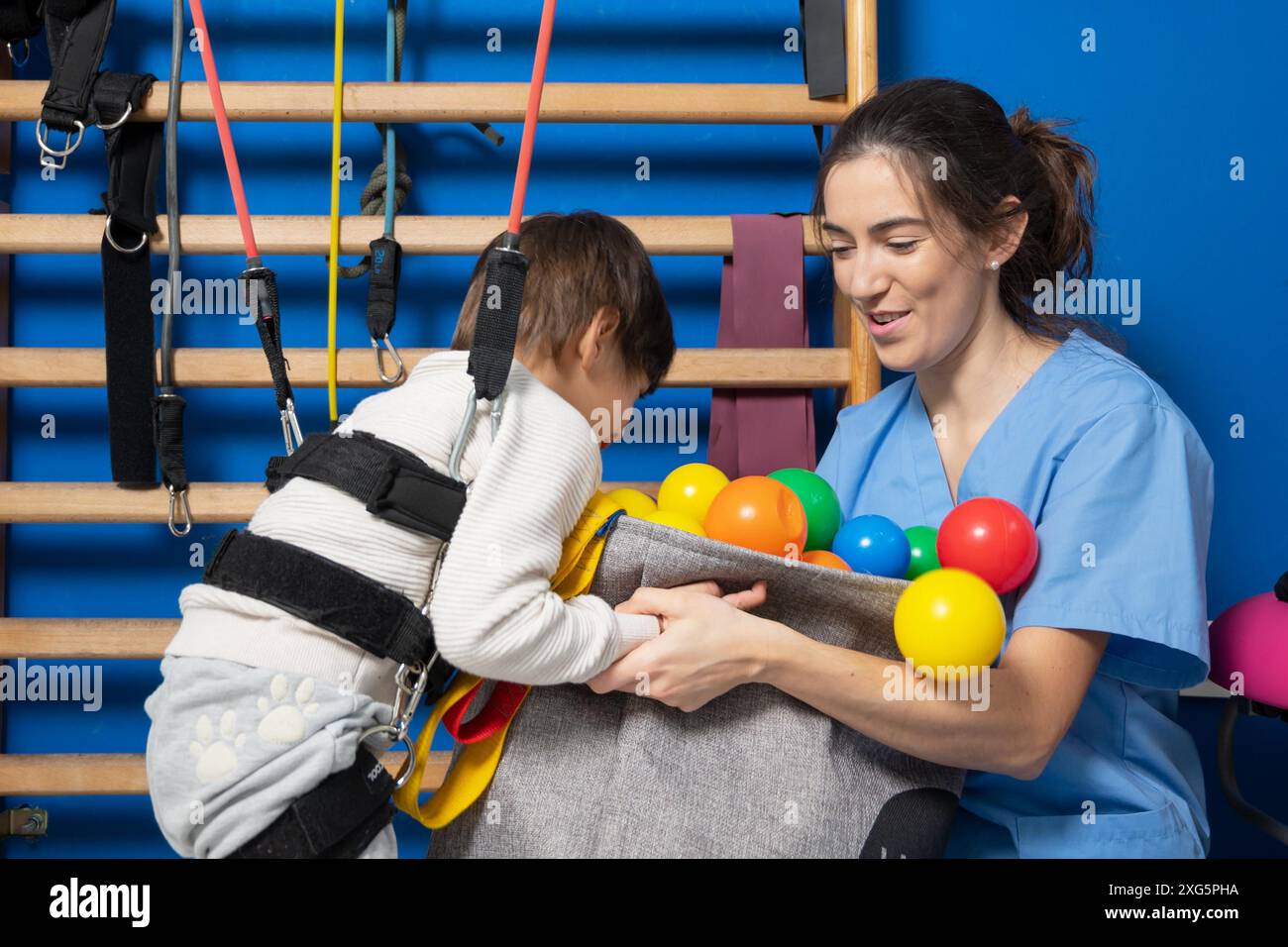 Niedliches Kind mit Zerebralparese, das muskuloskelettale Therapie im Krankenhaus macht, während es lacht und Spaß hat, hochwertiges Foto Stockfoto