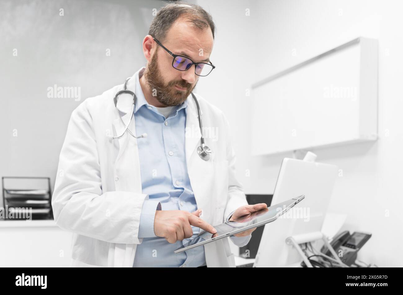 Männlicher Arzt mit weißem Mantel und Stethoskop mit Tablet, Netzwerkanbindung im Krankenhauszimmer, Medizintechnik-Netzwerkkonzept. Hohe Qualität Stockfoto