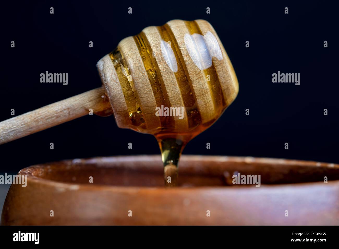 Natürlicher flüssiger Honig in einer Holzschale, echter Bienenhonig aus der Nähe Stockfoto