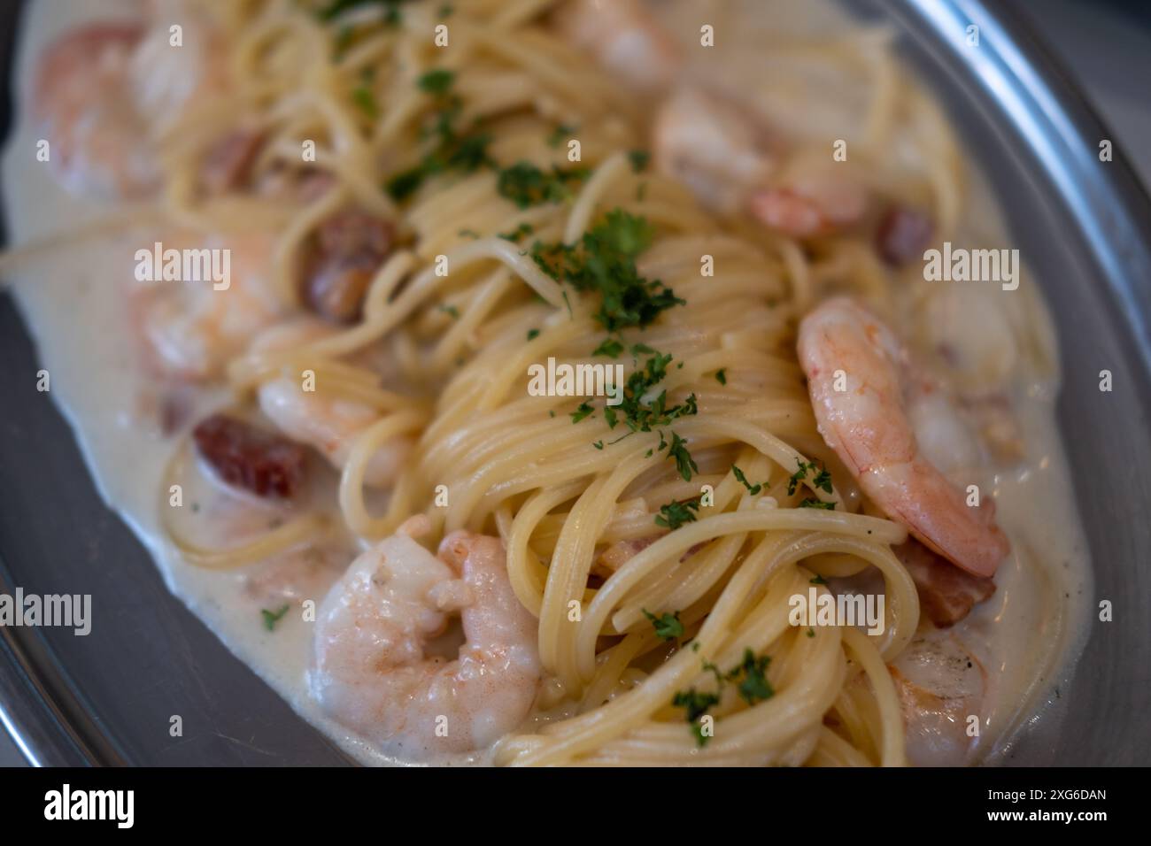 Weißwein, Sahne, Garnelen und Spaghetti mit Speck, serviert auf einem Teller Stockfoto