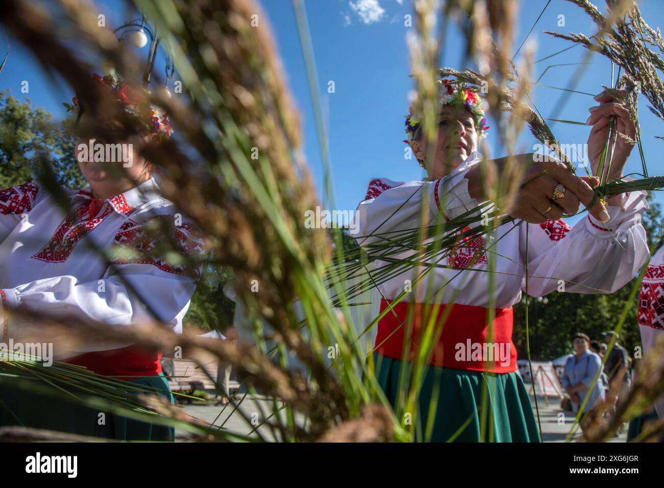 Moskau, Russland. Juli 2024. Frauen weben Kränze aus Wildblumen während einer Feier des belarussischen Feiertags „Kupalle“ im Ostankino-Park in Moskau, Russland. Kupalle oder Ivana Kupala Day, auch bekannt als Ivana-Kupala oder Kupala Night, ist eine traditionelle heidnische Feiertagsfeier in ostslawischen Kulturen. Mädchen kreieren und tragen Blumenkränze und führen verschiedene Rituale aus. Anfangs war Ivana-Kupala ein heidnischer Fruchtbarkeitsritus, der auch mit der Feier der Sommersonnenwende verbunden war, wenn die Nächte am kürzesten sind Stockfoto