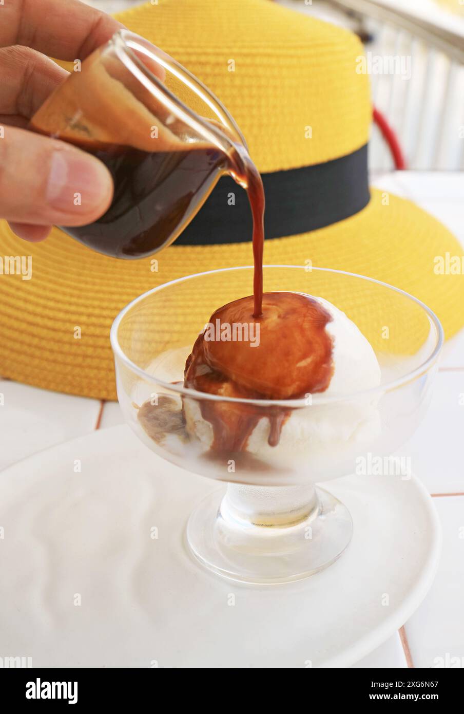 Mit der Hand einen Espresso auf Vanilleeis für eine Tasse Affogato gießen Stockfoto