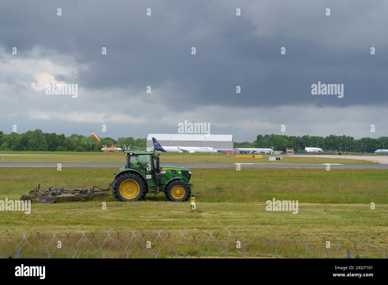 John Deere Traktor, der das Gras am Flughafen Manchester schneidet Stockfoto