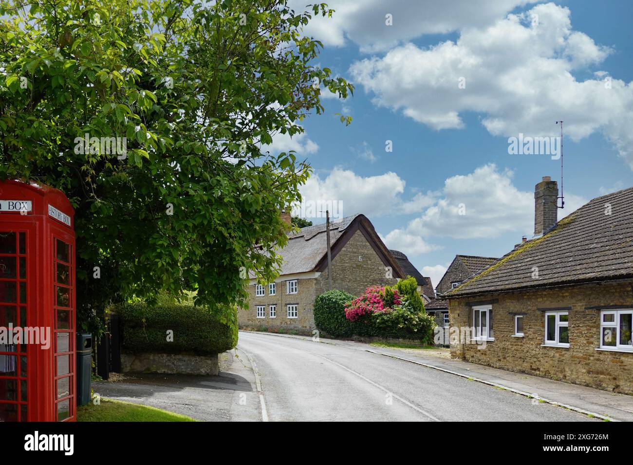 Harrington, Northamptonshire, England, Großbritannien - hübsche strohgedeckte Hütten und eine rote Telefonzelle in der Village High Street Stockfoto