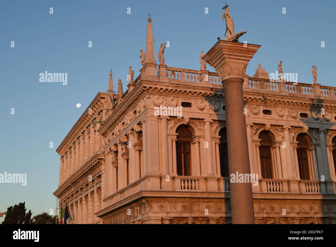 Mit Blick auf die Säulen des Löwen von St. Markus und St. Theodore und Statuen auf der Balustrade, Biblioteca Nazionale Marciana vor einem blauen Himmel Stockfoto