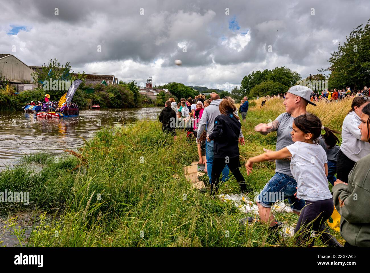 Lewes, Großbritannien. Juli 2024. Lokale Menschen in selbstgemachten Flößen nehmen am Lewes Raft Race auf dem Fluss Ouse von Lewes nach Newhaven Teil. Das Raft Race ist eine jährliche Veranstaltung, die von Lewes Round Table zur Unterstützung lokaler Wohltätigkeitsorganisationen organisiert wird. Traditionell stellen sich die Zuschauer am Flussufer auf und werfen Eier und Mehl auf die Flöße, während sich die Menschen auf den Flößen mit selbstgemachten Schilden schützen. Quelle: Grant Rooney/Alamy Live News Stockfoto