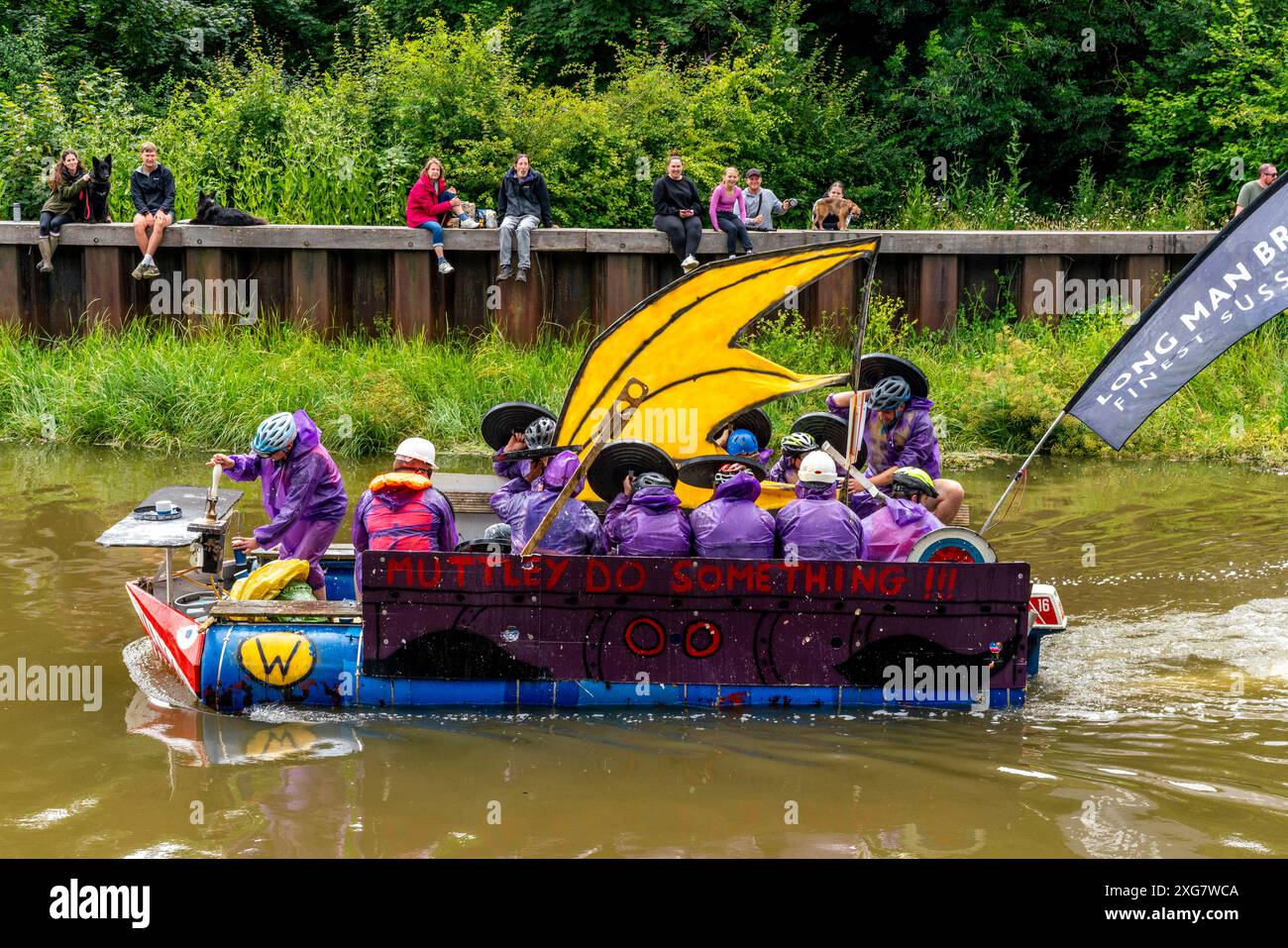 Lewes, Großbritannien. Juli 2024. Lokale Menschen in selbstgemachten Flößen nehmen am Lewes Raft Race auf dem Fluss Ouse von Lewes nach Newhaven Teil. Das Raft Race ist eine jährliche Veranstaltung, die von Lewes Round Table zur Unterstützung lokaler Wohltätigkeitsorganisationen organisiert wird. Traditionell stellen sich die Zuschauer am Flussufer auf und werfen Eier und Mehl auf die Flöße, während sich die Menschen auf den Flößen mit selbstgemachten Schilden schützen. Quelle: Grant Rooney/Alamy Live News Stockfoto