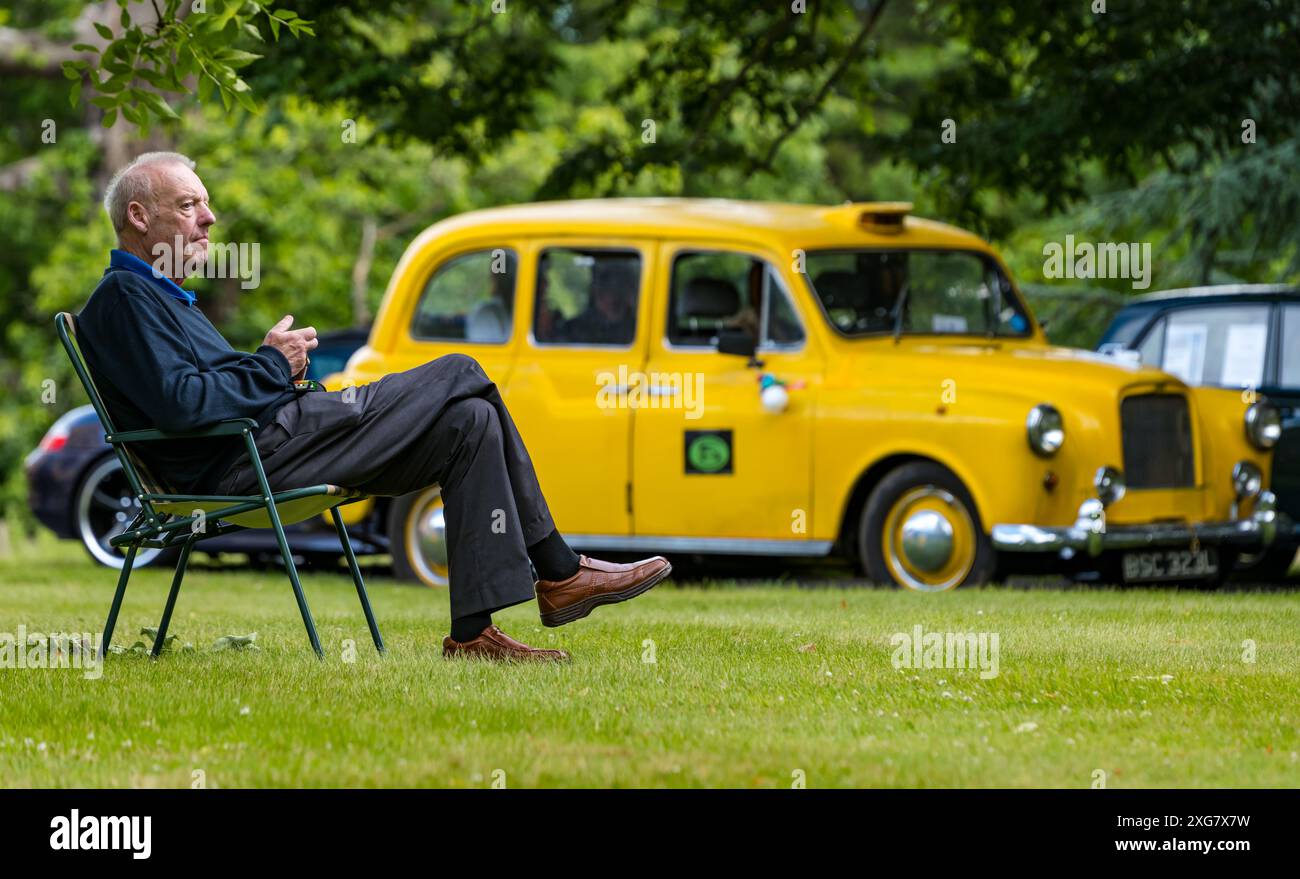 East Lothian, Schottland, Großbritannien, 7. Juli 2024. Räder der Vergangenheit: Die schottische Vereinigung der Fahrzeugliebhaber führt die Besitzer von Oldtimern durch die Landschaft zum malerischen Gelände von Lennoxlove. Im Bild: Ein Mann entspannt sich in einem 1972 gelben Austin Taxi. Quelle: Sally Anderson/Alamy Live News Stockfoto
