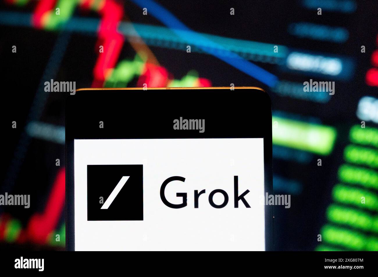 In dieser Foto-Illustration wird der Chatbot-Teil von Elon Musks künstlicher Intelligenz, X, Grok, auf einem Smartphone mit einem wirtschaftlichen Börsenindex-Diagramm im Hintergrund angezeigt. Stockfoto